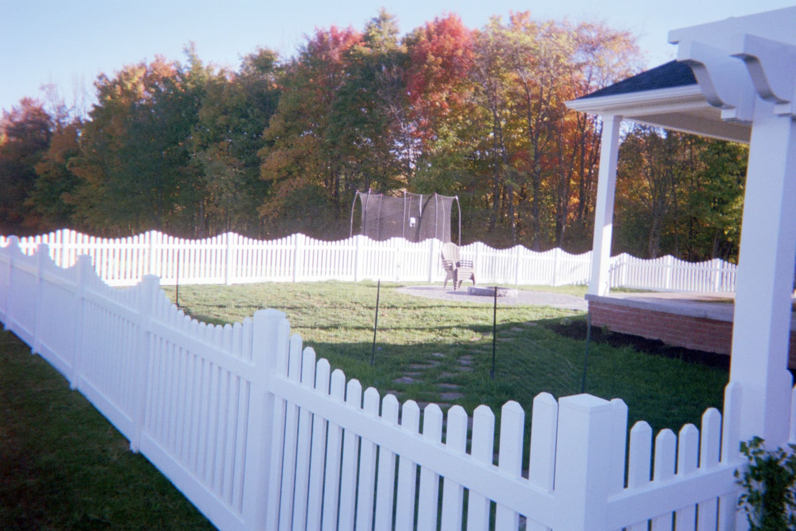 Backyard with trampoline and white fence